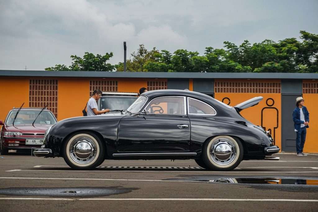 a black car parked in a parking lot next to other cars Porsche 356